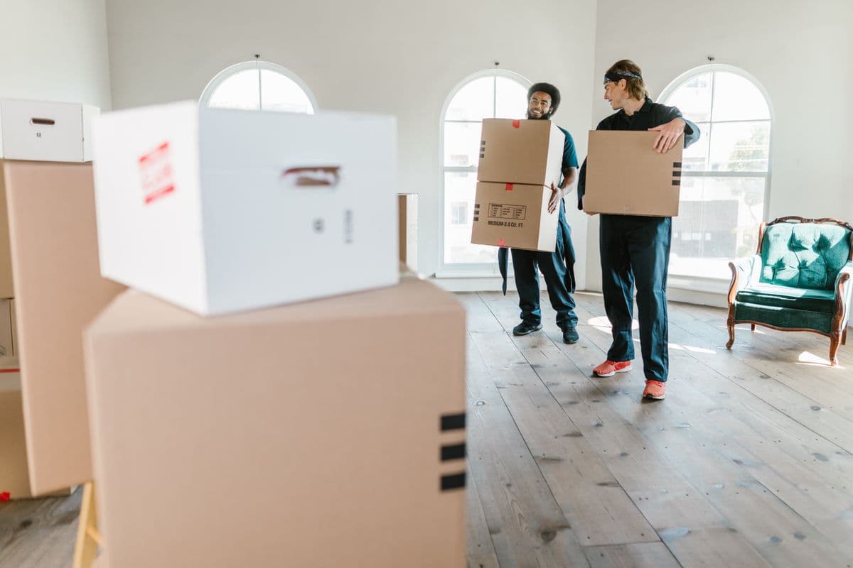 Magic Carpet Movers crew carrying boxes into a home